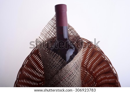 Closeup of one glass green wine corked bottle with alcohol fresh grapes beverage with cork wrapped in burlap fabric lying on wattled napkin on white background copyspace, horizontal picture