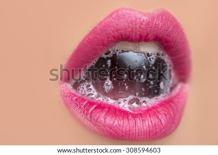 Closeup of sexual open female mouth of pretty young woman with foam beverage bubbles on bright pink lips on tan beige face, horizontal picture