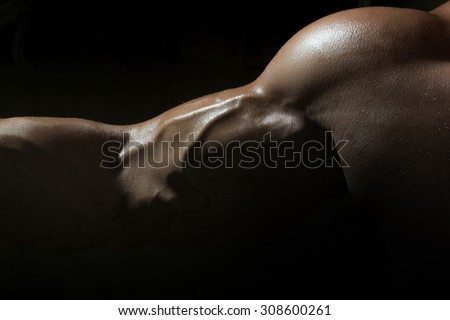 Closeup of sexy tan swollen muscular male biceps of young bodybuiding man with athlete wet strong body on black studio background, horizontal picture
