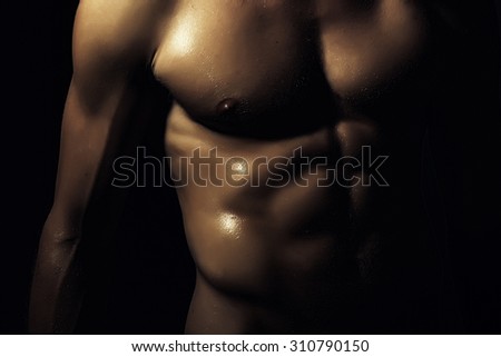Closeup of young naked man with sexual strong muscular beautiful tan wet body with sexy chest and nipples standing on black backgrouns, horizontal picture