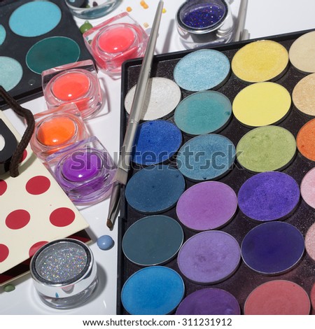 Set of different professional eyeshadow palette red orange green violet pink yellow purple black beige brown colors foundation powder and make-up brushes on white background, square picture