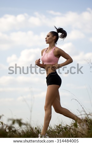 Full length one pretty slim young brunette active woman with straight beautiful body in sportswear on morning running outdoor side view on cloud blue sky background, vertical picture