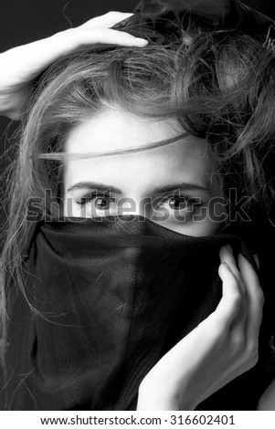 Portrait of one beautiful sensual woman with big eyes holding with hand very thin cobwed fabric black and white closeup, vertical picture