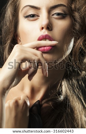 Portrait of one sensual young woman with big eyes pink lips and stylish haircut holding finger in open mouth looking forward closeup, vertical picture