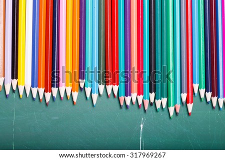 Palette set of colorful sharp pencils brown red yellow blue green violet pink purple lilac grey black white and orange colors lying in row on blackboard studio background copyspace, horizontal picture