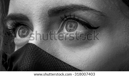 Portrait of one beautiful sensual woman with big eyes and face covered with very thin cobwed fabric looking away black and white closeup, horizontal picture