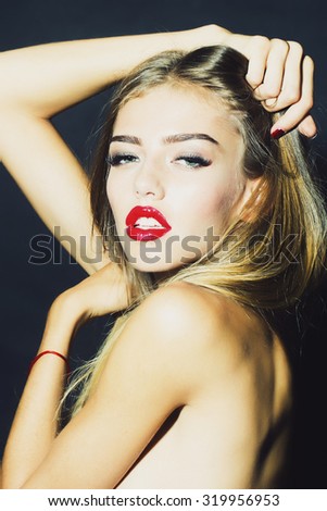 Portrait of beautiful sexual undressed girl with long eyelashes lush hair and red lips holding raised hands near face and head looking forward in studio on black background, vertical picture