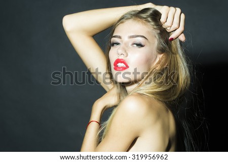 Portrait of beautiful sexual stripped lady with long eyelashes lush hair and red lips holding raised hands near face and head looking forward in studio on black background, horizontal picture