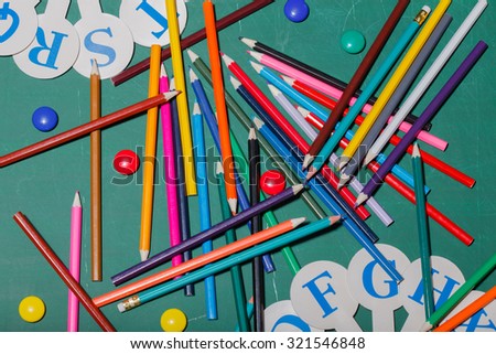 Palette set of colorful sharp pencils brown red yellow blue violet pink purple lilac grey black white and orange colors lying in row with other school tools on green background, horizontal
