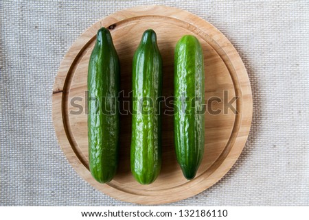 Three cucumbers on wooden cutting board