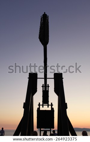 Silhouette of a medieval siege weapon at dusk in Alghero, Italy