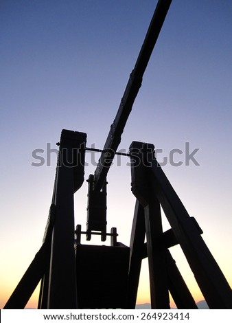 Silhouette of a medieval siege weapon at sunset in Alghero, Italy