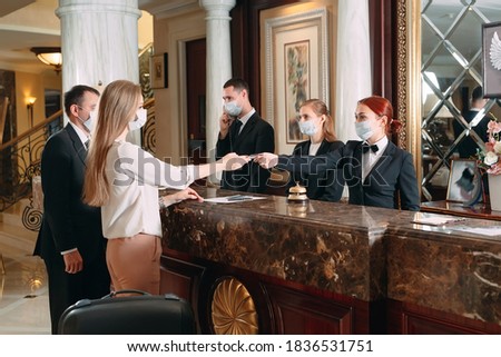 Check in hotel. receptionist at counter in hotel wearing medical masks as precaution against virus. Young woman on a business trip doing check-in at the hotel