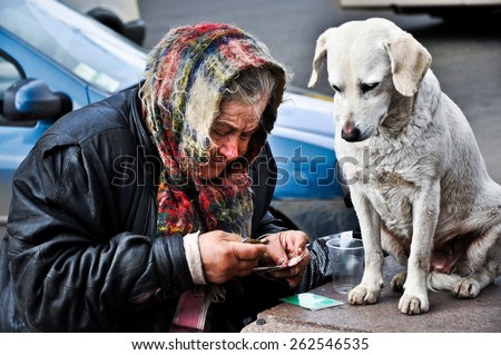 an old woman, a beggar, said money with the dog on the streets of Kiev