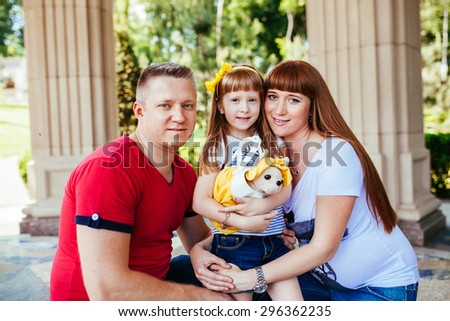 Young and beautiful family in the park, a pregnant mother, father, daughter