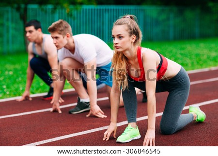 Athletic young people on track starting to run. Healthy fitness concept with active lifestyle.