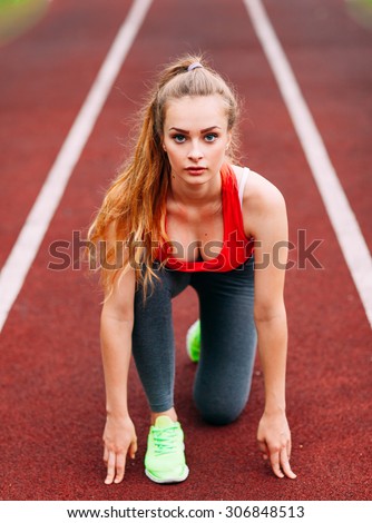 Athletic woman on track starting to run. Healthy fitness concept with active lifestyle.