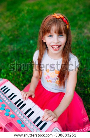 Little girl playing on a toy piano in the park