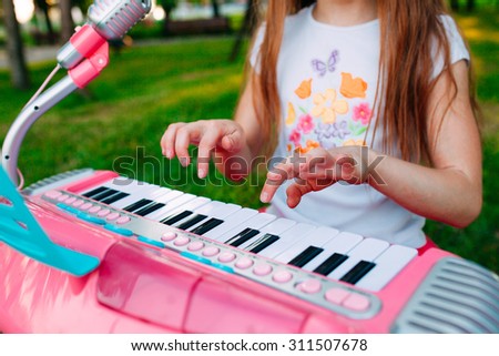 Little girl playing on a toy piano in the park