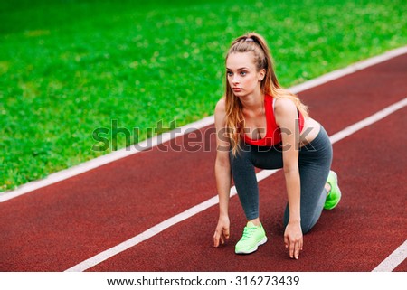 Athletic woman on track starting to run. Healthy fitness concept with active lifestyle.