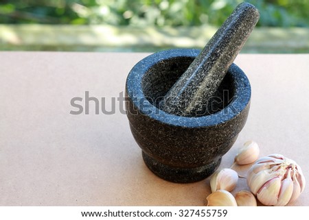 Stone mortar and pestle with garlic  on the wooden board in selective focus