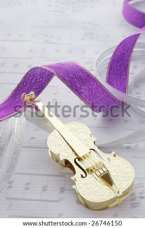 Golden violin with ribbons on music note background