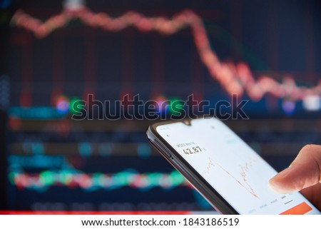 Investor analyzing stock market investments on a smartphone. Person trading stocks on a smartphone. Falling share prices at the stock exchange. Stock market crash. Trader at the stock exchange.