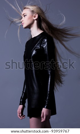 Studio shot of woman in leather dress with long blowing hair. Profile