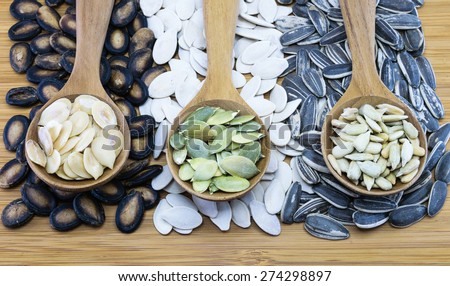 Edible seeds in wood spoon on wood background; From left, watermelon seed, pumpkin seed, sunflower seed