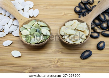 Edible seeds in wood spoon on wood background; From left, pumpkin seed, watermelon seed