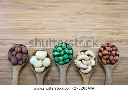 Mixed nuts in wood spoon on wood background, From left-Almond, Macadamia, Green Peanuts, Cashew nut, Skin red peanuts