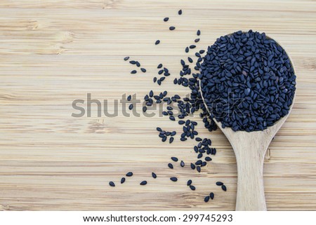 black sesame in wood spoon on wood background