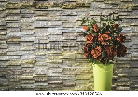 Red rose bouquet in green bucket with stone wall background in vintage style