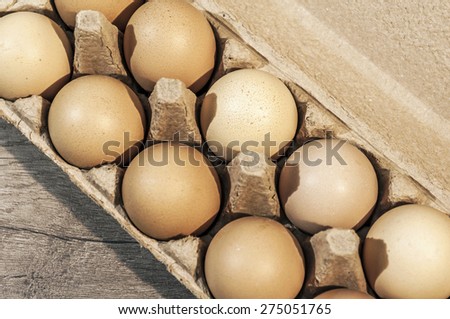 Ten brown eggs in a carton package on a wooden table, eggs