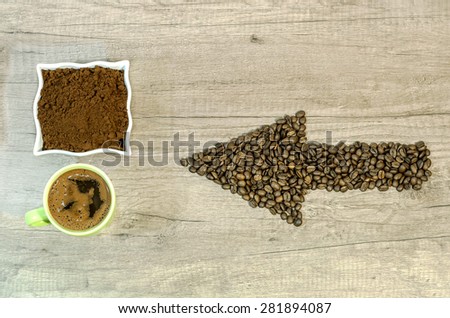 Arrow from the coffee beans with a cup of fresh ground coffee and fresh cup of coffee on table