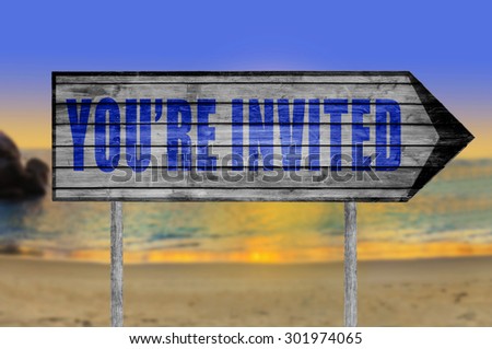 You\'re Invited! wooden sign with a beach on background