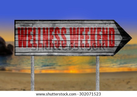Red Wellness Weekend wooden sign with on a beach background