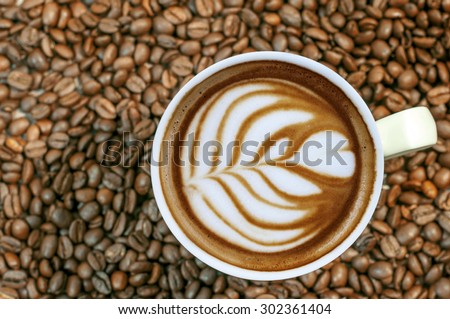 Coffee bean background with cup of fresh hot espresso coffee art close up