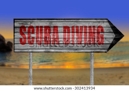 Red Scuba Diving wooden sign with a beach on background
