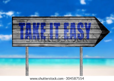 Take It Easy wooden sign with on a beach background
