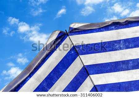 Blue and white umbrella and blue sky symbolizing vacationing in summer