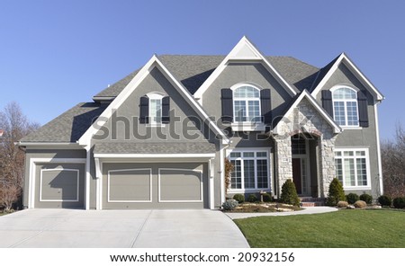 Neat average suburban family house living in North America under bright blue sky.