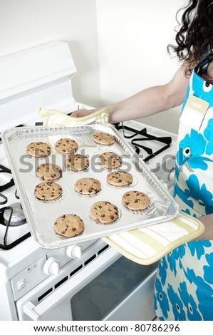 Beautiful woman baking cakes and cookies in a white home kitchen oven