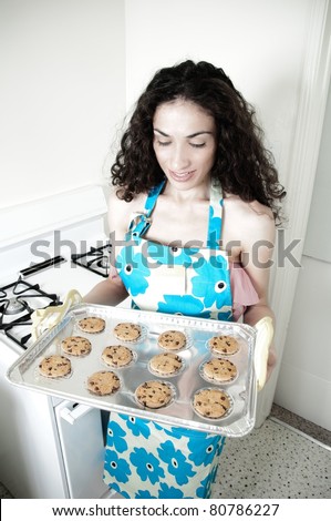 Beautiful woman baking cakes and cookies in a white home kitchen oven