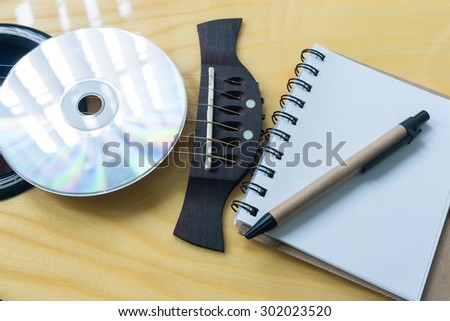 Music recording scene with guitar, notebook and CD.