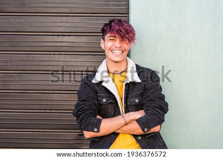 Cheerful young happy boy teenager hispanic race smile and laugh in front of the camera in posed portrait - two colors background urban style - youth teenager enjoy - violet diversity hair