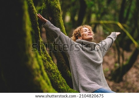 Overjoyed happy woman enjoying the green beautiful nature woods forest around her - concept of female people and healthy natural lifestyle - happiness emotion and adult lady opening arms  Imagine de stoc © 