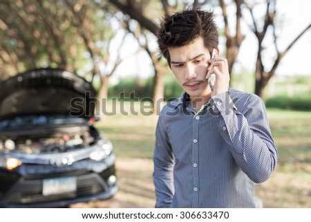 Young businessmen talking on a cell phone by a broken car On Country Road Phoning For Help
