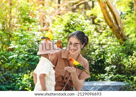 Asian young woman feeding birds on hand and showing to her daughter in the zoo. Foto d'archivio © 