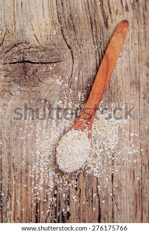 oat bran in wooden spoon on wooden background